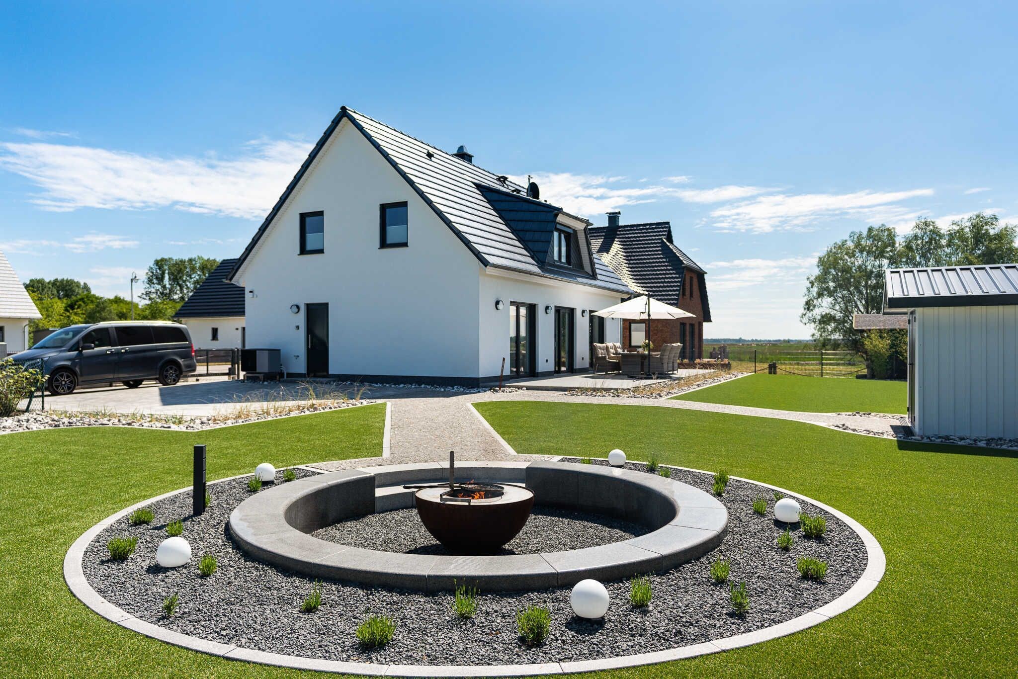 Das Ferienhaus Josefine im Ostseebad Karlshagen auf der Insel Usedom. Eine Außenansicht mit gepflegtem Garten, Terrasse, Feuerstelle und gepflastertem Zugang.
