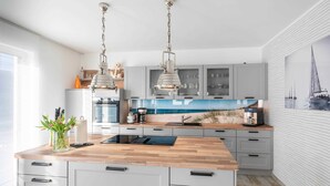 Een moderne keuken met een houten kookeiland, grijze kastjes en hanglampen.
