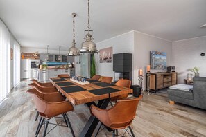 A modern kitchen with a dining area, featuring a wooden table and leather chairs.