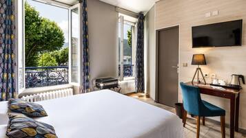 Ein Hotelzimmer mit Bett, Schreibtisch, Stuhl, Fernseher und Blick ins Freie.