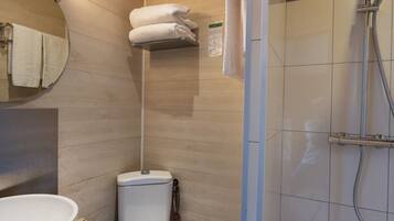 A bathroom with a wooden ceiling, a white toilet, a sink, and a shower area.