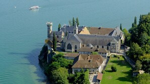 A historic building with a large courtyard and a lake view. - Hotel Beau Rivage (Aix-les-Bains)