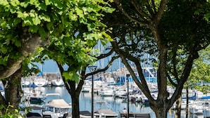 A marina with boats docked, benches, and trees providing shade. - Hotel Beau Rivage (Aix-les-Bains)