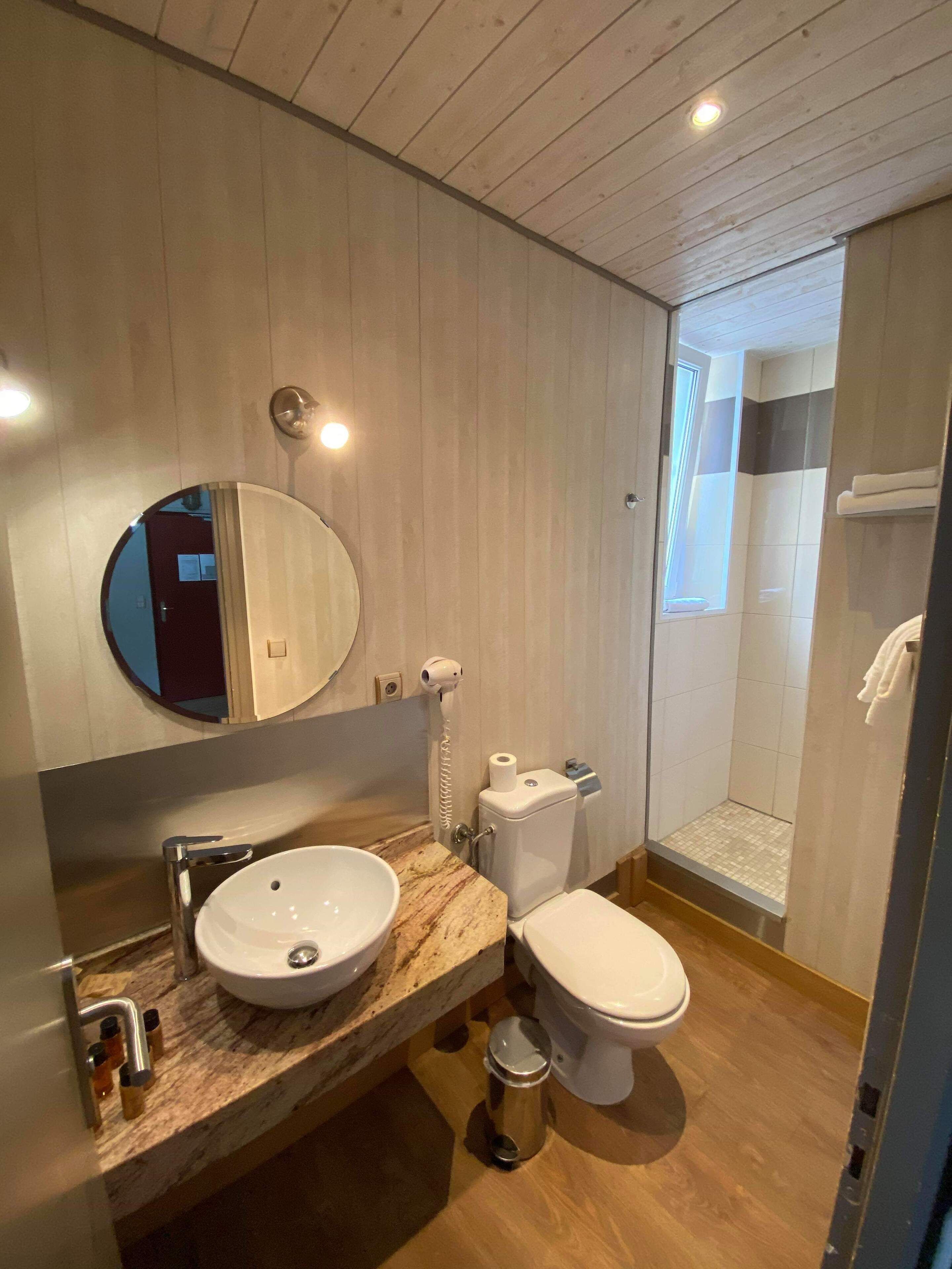 A modern bathroom with a marble sink, a toilet, and a shower area.