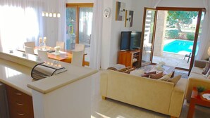Ein modernes Wohnzimmer mit Sofa, Fernseher und Essbereich mit Tisch und Stühlen.