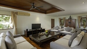 A modern living room with a flat-screen TV, a ceiling fan, and a wooden coffee table.