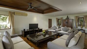 A modern living room with a flat-screen TV, a ceiling fan, and a wooden coffee table.