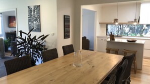 A modern kitchen with white cabinets, a built-in dishwasher, and a window with a view of greenery. - Torquay - SpringHaven Beach House (Torquay)