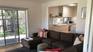 A modern living room with a sectional sofa, a small ottoman, and a remote control on a tray. - Torquay - SpringHaven Beach House (Torquay)