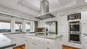 Une cuisine moderne avec des meubles blancs, des appareils en acier inoxydable et un grand îlot central.