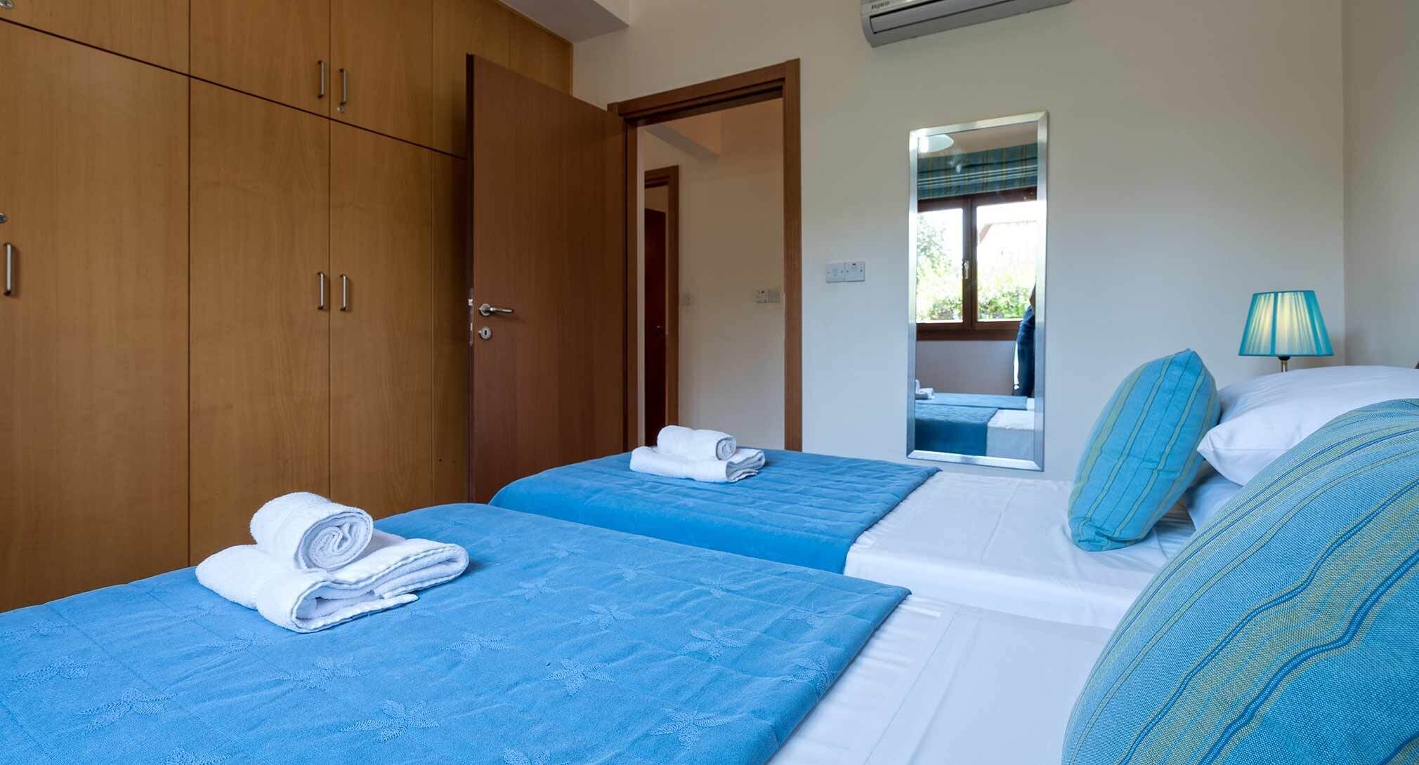Quarto de hotel com duas camas, um guarda-roupa, um espelho e uma janela com vista.