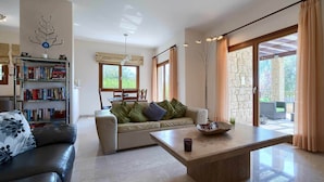 A modern living room with a sofa, a coffee table, and a bookshelf. - Villa HG01 - Madelini (Kouklia)