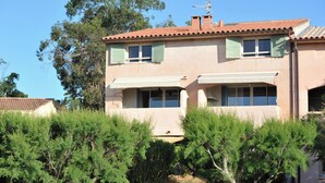 Un bâtiment à deux étages, doté d’un toit recouvert de tuiles, de volets verts et d’une cheminée.