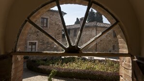 Ein Bogenfenster mit Blick auf ein Steinhaus und einen Garten.