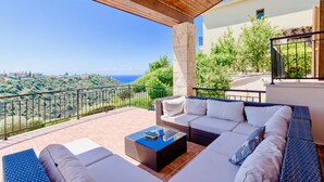 A balcony with a wicker sofa, a coffee table, and a view of the sea. - Villa 98 - Helidoni (Kouklia)