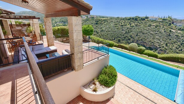 A poolside area with a pergola, seating, and a view of a mountainous landscape. - Villa 98 - Helidoni (Kouklia)