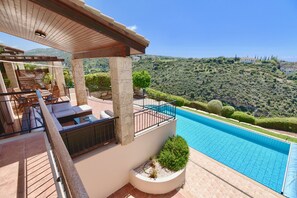 Ein Poolbereich mit einer Pergola, Sitzgelegenheiten und Blick auf eine gebirgige Landschaft.
