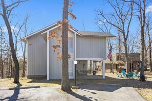 A white building with a porch, surrounded by trees and a clear sky.