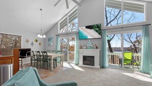Un salón amplio con chimenea, ventanas grandes, televisor y comedor.