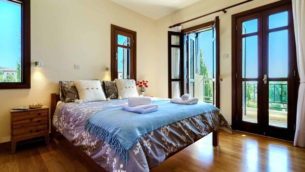Un dormitorio con cama, mesita de noche, ventana y puerta.