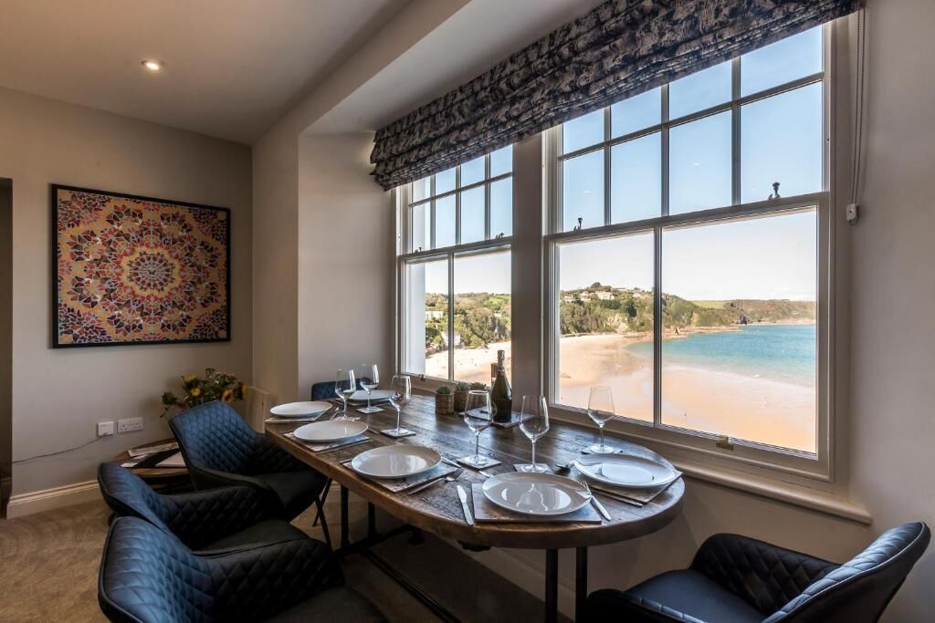 A dining area with a view of the beach, a large window, and a patterned wall decoration.