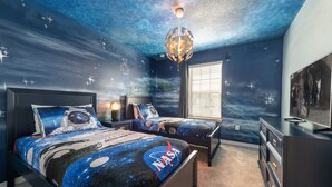 A bedroom with two beds, a dresser, and a ceiling mural of space. - Fascinating 5 BR Home Near Disney 8931 (Kissimmee)