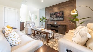 A living room with a sofa, armchair, coffee table, and a fireplace. - Fascinating 5 BR Home Near Disney 8931 (Kissimmee)