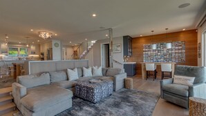 Una sala de estar moderna con un sofá modular, una mesa de centro y un comedor con una mesa y sillas de madera.
