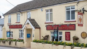 A traditional pub with a sign reading "The Polmore Inn" and "Traditional ales & game cooked food." - The Poltimore Inn (South Molton)