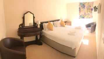 A hotel room with a bed, a nightstand, a dresser, a chair, and a mirror.
