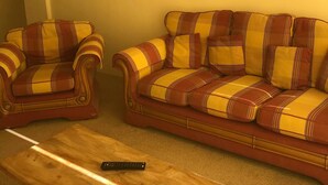 A living room with two striped sofas, a wooden coffee table, and a framed landscape painting on the wall. - The Poltimore Inn (South Molton)