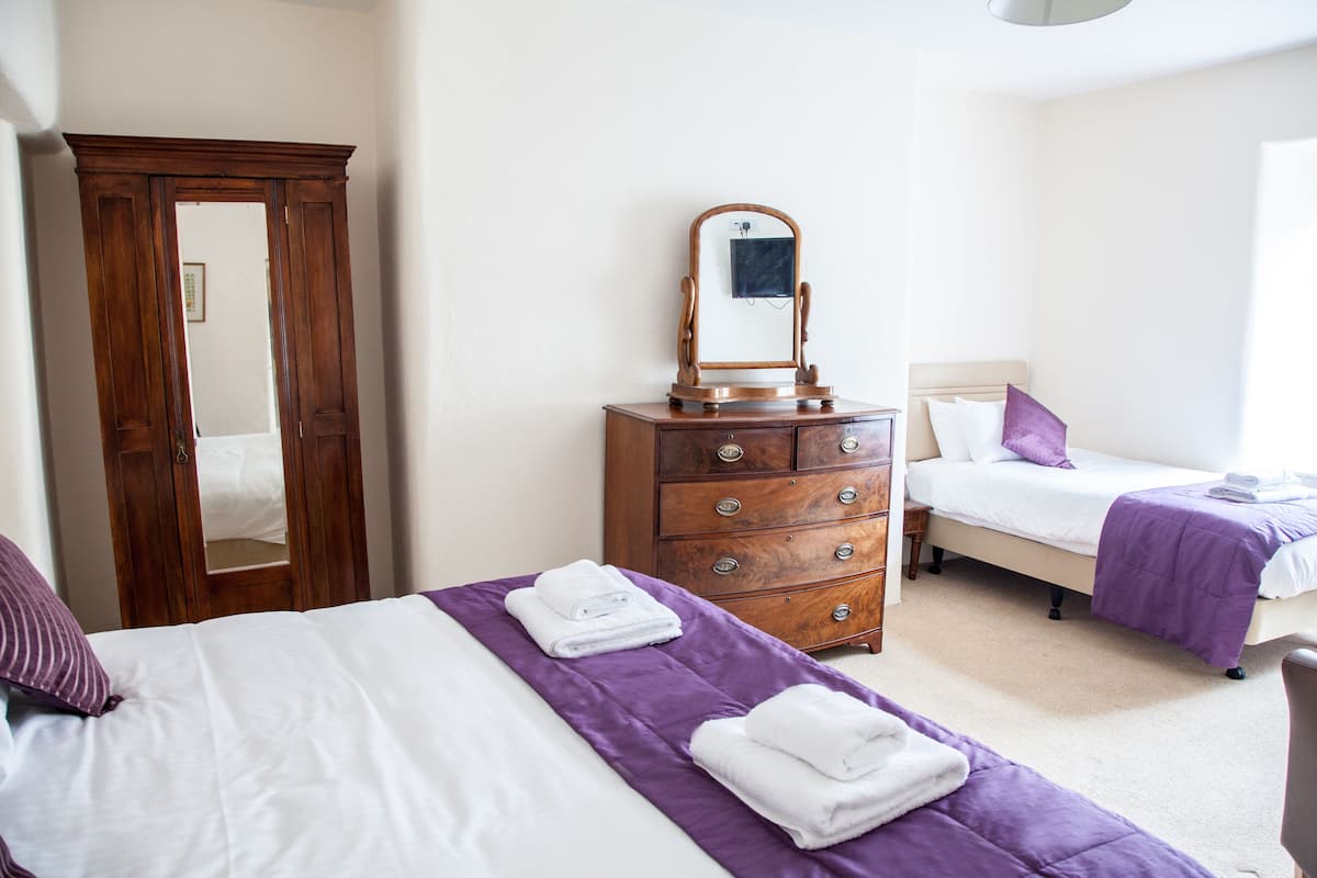 A hotel room with two beds, a wooden wardrobe, a dresser, and a mirror.