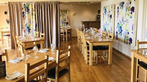A dining area with wooden tables and chairs, arranged for service. - The Poltimore Inn (South Molton)