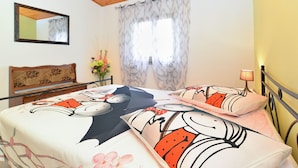 A bedroom with a wooden ceiling, a bed with floral and cartoon-themed bedding, a nightstand with a lamp, a mirror on the wall, and a window with curtains. - Apartment 2018/28685 (Istria - Pula), 2500m from the beach (Pula)