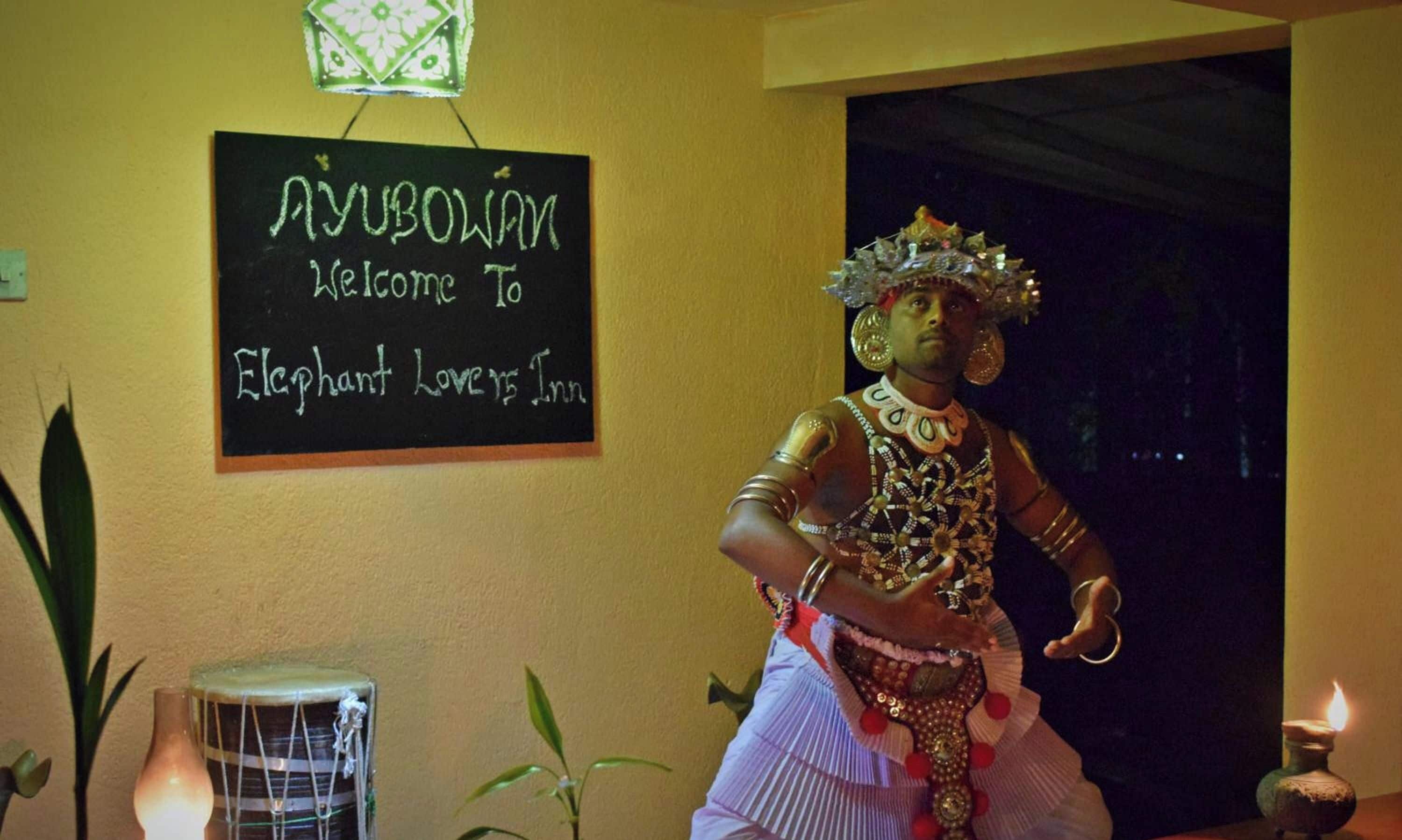 A sign welcoming to Elephant Lovers Inn, a room with a drum, a candle, and a plant.