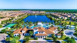 Een resort met een centraal gelegen zwembad, tennisbanen en een groot gebouw met een betegeld dak.