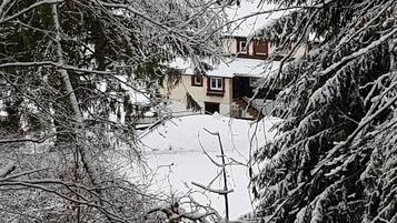 Eine verschneite Landschaft mit einem Haus im Hintergrund.