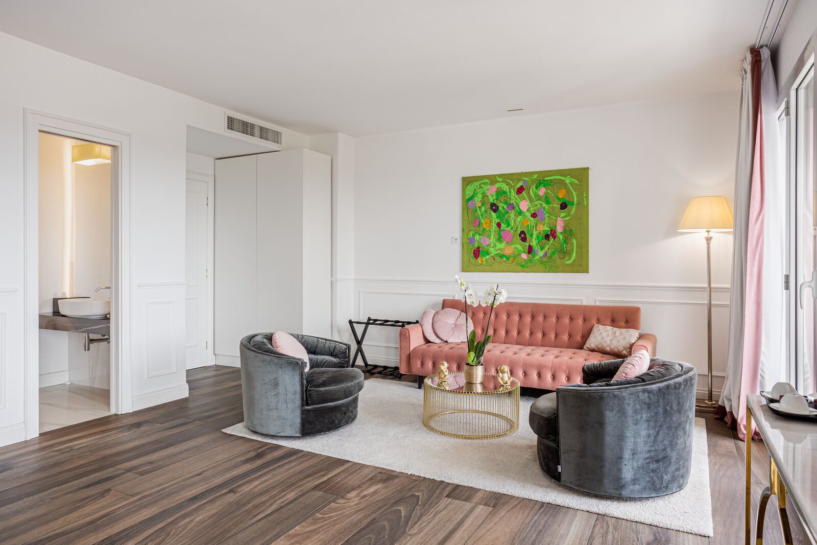 A modern living room with a sofa, two armchairs, a coffee table, and a painting on the wall.