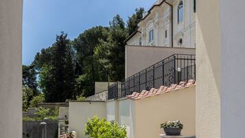 Une cour offrant une vue sur un bâtiment doté d’un clocher, entouré de verdure et surplombant un ciel dégagé.
