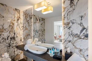 A modern bathroom with marble walls, a dual sink vanity, and a large mirror.