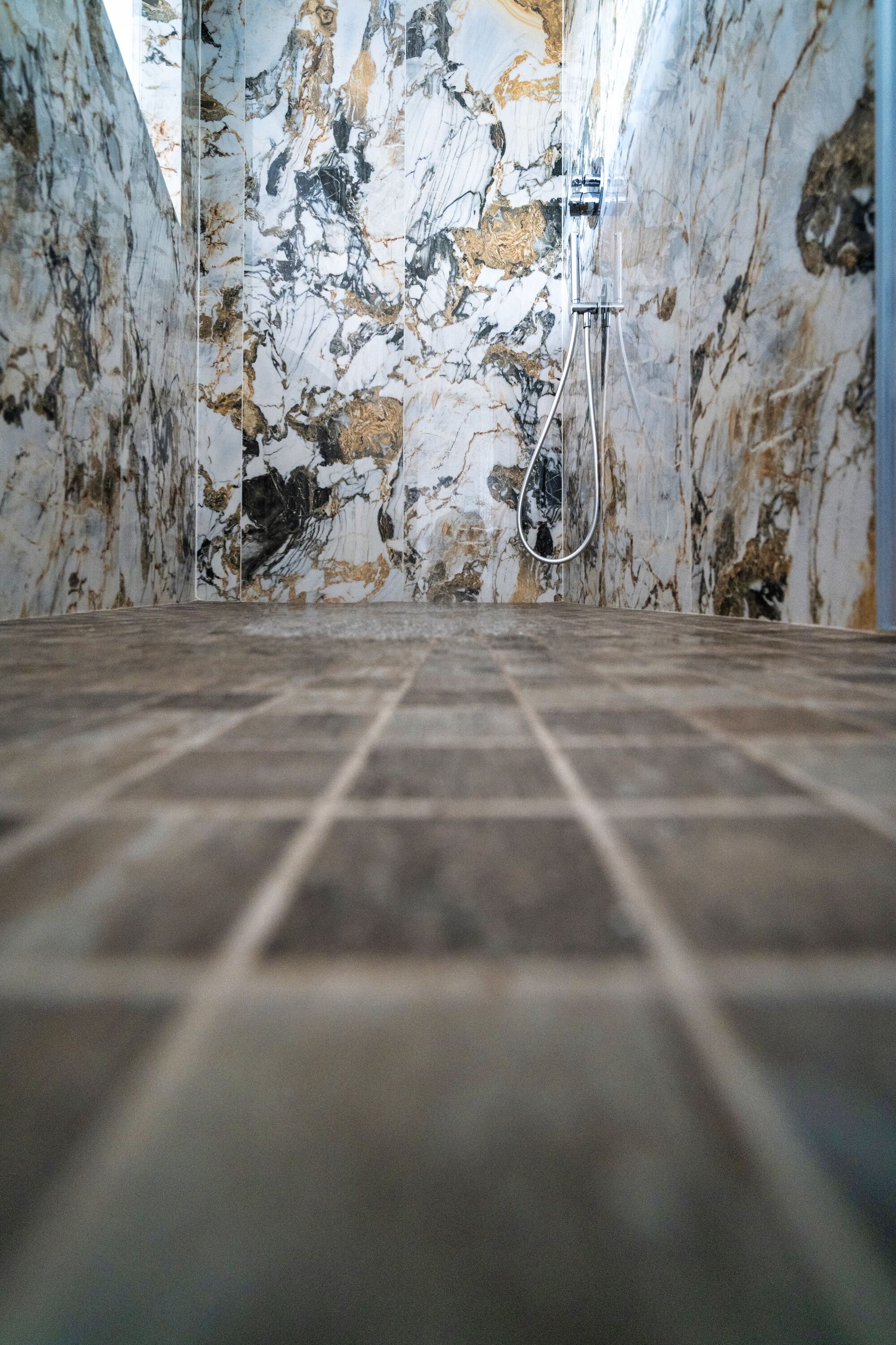 A bathroom with a marble wall and a shower area.