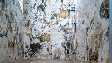 A bathroom with a marble wall and a shower area.