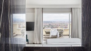 A modern hotel room with a large window, a bed, a table with chairs, and a shower area. - Monastero dei Santi (Rome)