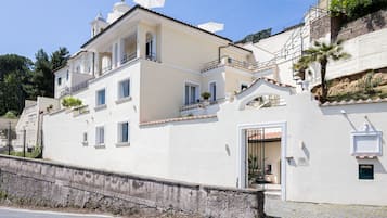 A two-story building with a balcony, a gate, and a small garden area.