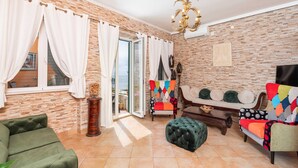 A living room with a brick wall, a sofa, a chair, a coffee table, and a chandelier. - Villa Adrian (Dubrovnik)
