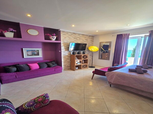 A room with a purple sofa, a bed, a TV, and a wooden cabinet. - Villa Adrian (Dubrovnik)