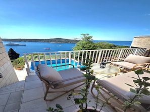 A balcony with a pool, outdoor furniture, and a view of the sea.