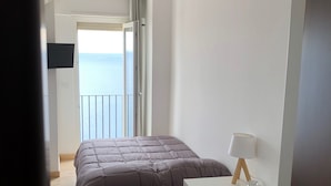 A bedroom with a bed, a desk with a chair, a lamp, and a TV on the wall. - Villa Jole Taormina (Taormina)