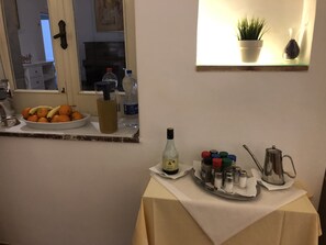 A kitchen counter with a fruit bowl, a bottle of olive oil, and a tray of condiments.