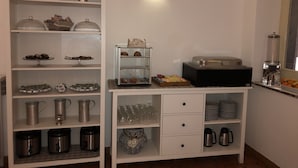 A kitchen with a coffee maker, a food display, and storage shelves. - Villa Jole Taormina (Taormina)